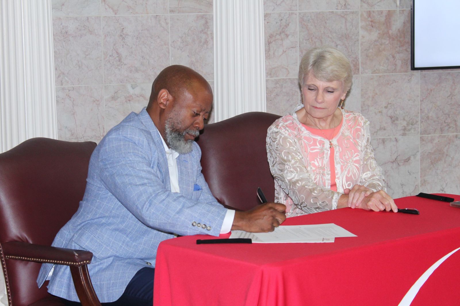 Tony Smith, chairman of The Chamber Board of Directors, signs the Memorandum of Understanding detailing the BOGO Scholarship as Dr. Kathy Murphy, president of Gadsden State, looks on.