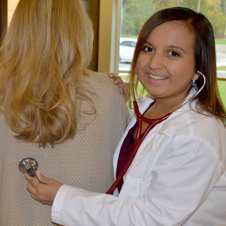 A health sciences student wearing a hearing aid using a stethoscope  